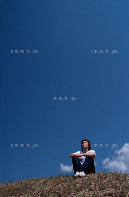 丘の上に座って見上げる日本人男の子 の写真素材 イラスト素材 アマナイメージズ