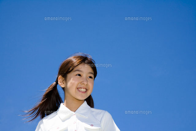 青空を背景に笑顔の女の子 a の写真素材 イラスト素材 アマナイメージズ