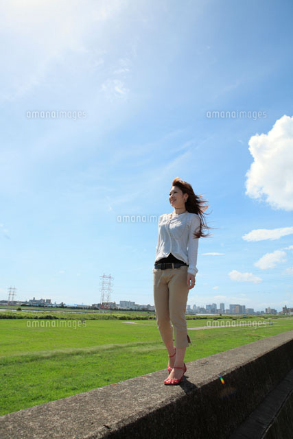 堤防を歩く女性 の写真素材 イラスト素材 アマナイメージズ