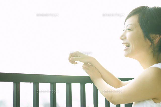 ベランダの手すりによりかかる女性 の写真素材 イラスト素材 アマナイメージズ
