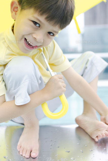 黄色い傘をさす裸足の男の子 の写真素材 イラスト素材 アマナイメージズ