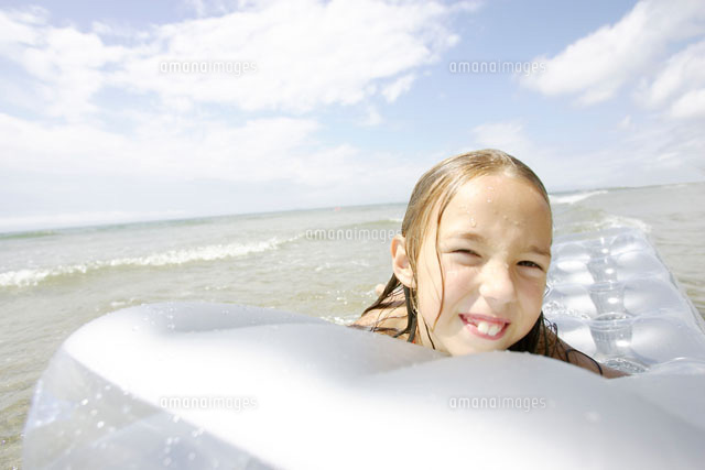 ビーチマットで海に浮く女の子 の写真素材 イラスト素材 アマナイメージズ