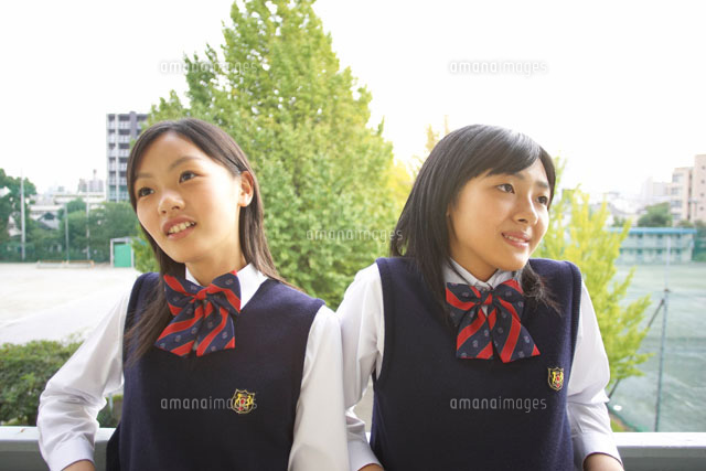 ベランダの手すりに凭れる2人の女子中学生 の写真素材 イラスト素材 アマナイメージズ