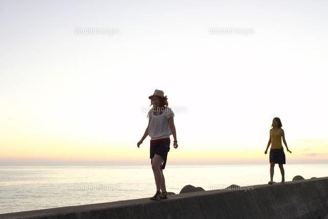 堤防を歩く2人の女の子 の写真素材 イラスト素材 アマナイメージズ