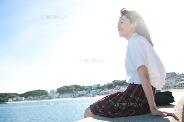 防波堤に座り海を眺めている女子高生 の写真素材 イラスト素材 アマナイメージズ