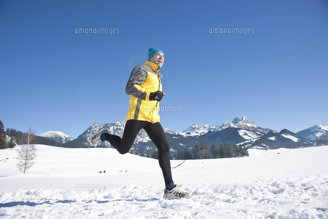 Man jogging in the snow in the mountains[20080026710]の写真素材 