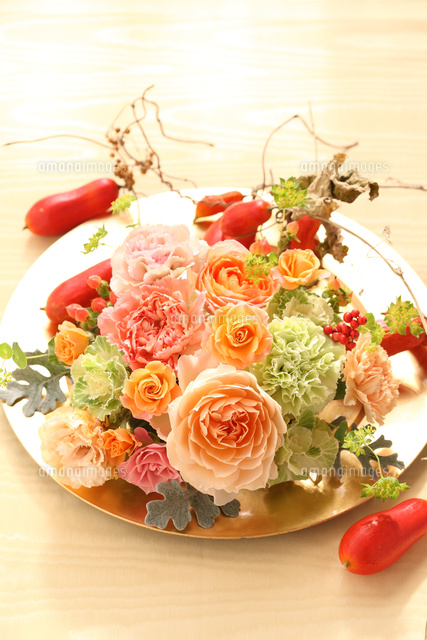お皿に飾られたオレンジの花のフラワーアレンジメント[21002003275]の