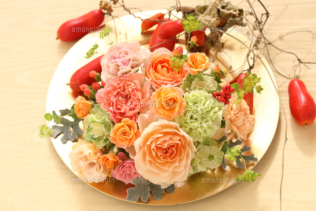 オレンジ色のフラワーデザイン皿 お皿に飾られたオレンジの花のフラワーアレンジメント[21002003276]の