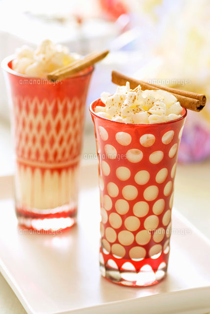 Two glasses of egg nog with whipped cream and cinnamon stick ...
