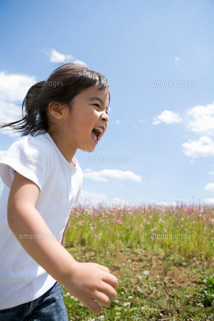 花畑前を笑顔で走る少女 の写真素材 イラスト素材 アマナイメージズ
