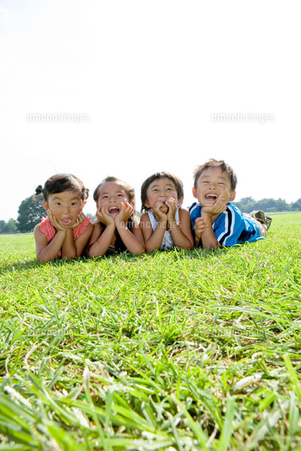 芝生に寝転がり頬杖をつく子供たち の写真素材 イラスト素材 アマナイメージズ
