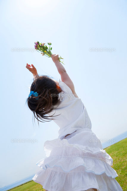 野の花を高く掲げる女の子の後ろ姿 a の写真素材 イラスト素材 アマナイメージズ
