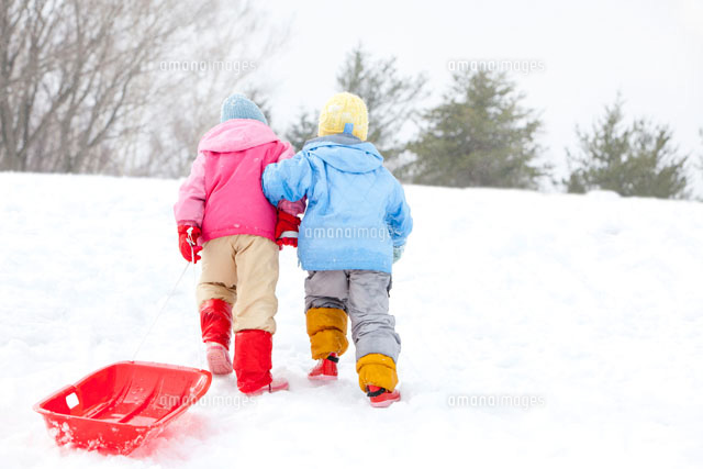 腕を組んで雪の斜面を登る子どもの後姿 の写真素材 イラスト素材 アマナイメージズ