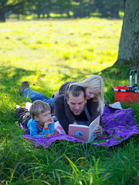 北欧の森で子供達に絵本を読む父 b の写真素材 イラスト素材 アマナイメージズ
