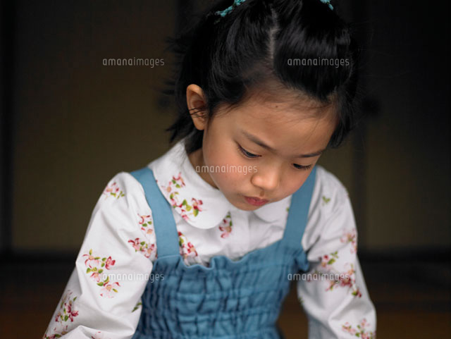 下を向いて何かを見つめている女の子 の写真素材 イラスト素材 アマナイメージズ