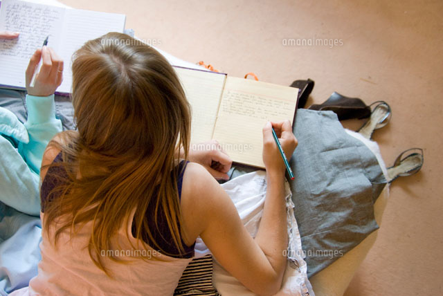 ベッドで日記を書く女性の後姿 の写真素材 イラスト素材 アマナイメージズ