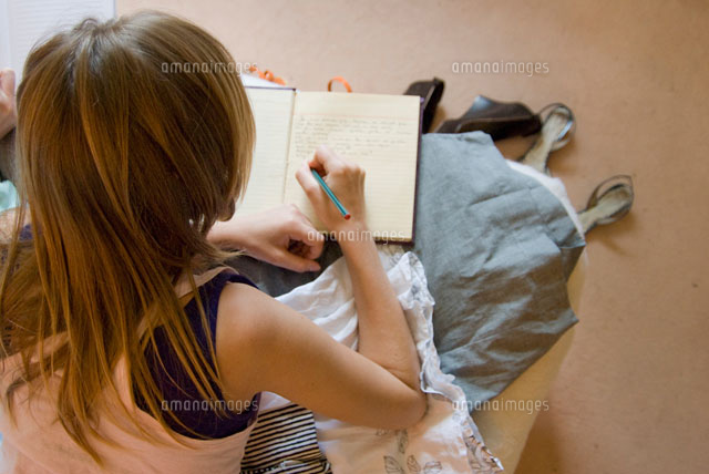 ベッドで日記を書く女性の後姿 a の写真素材 イラスト素材 アマナイメージズ