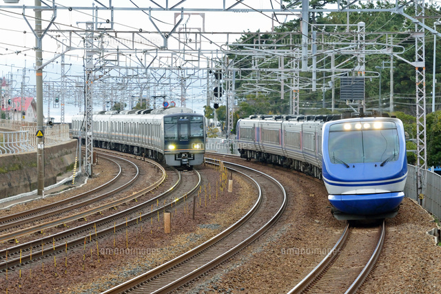 並走してカーブを曲がる山陽本線の207系普通電車とHOT7000系特急