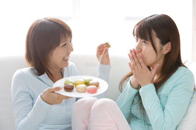 ソファでお菓子を食べる女性2人 a の写真素材 イラスト素材 アマナイメージズ