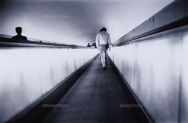 動く歩道を歩く人物の後姿 B W の写真素材 イラスト素材 アマナイメージズ
