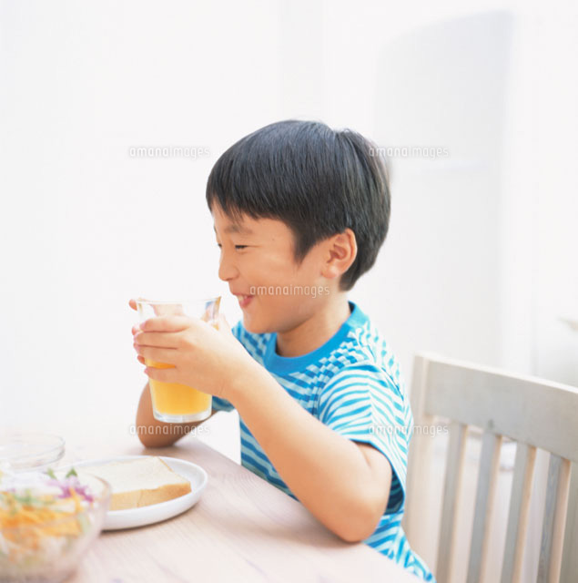 食卓でオレンジジュースを飲む日本人の男の子 の写真素材 イラスト素材 アマナイメージズ