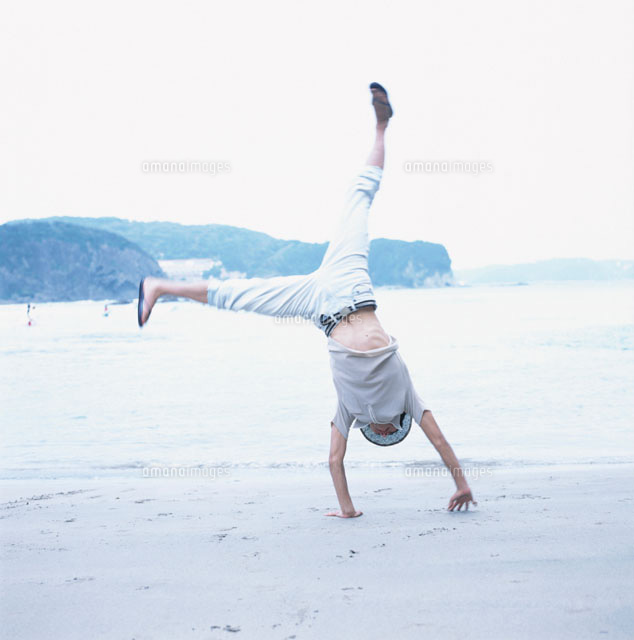 砂浜で側転する日本人男性 の写真素材 イラスト素材 アマナイメージズ