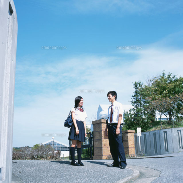 校門そばで話をする男子高校生と女子高校生 の写真素材 イラスト素材 アマナイメージズ