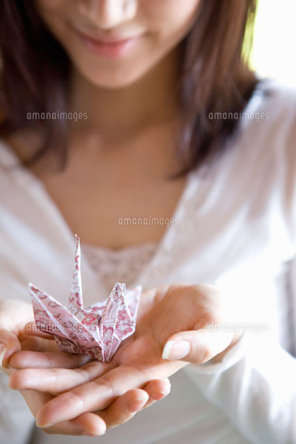 折り紙の鶴を手にのせた女性 の写真素材 イラスト素材 アマナイメージズ