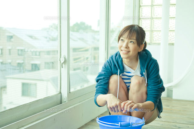 雑巾を絞りながら窓の外を見る女性 a の写真素材 イラスト素材 アマナイメージズ