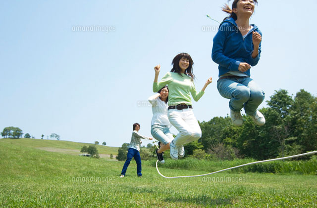 草原で縄跳びをしている3人の女性 の写真素材 イラスト素材 アマナイメージズ