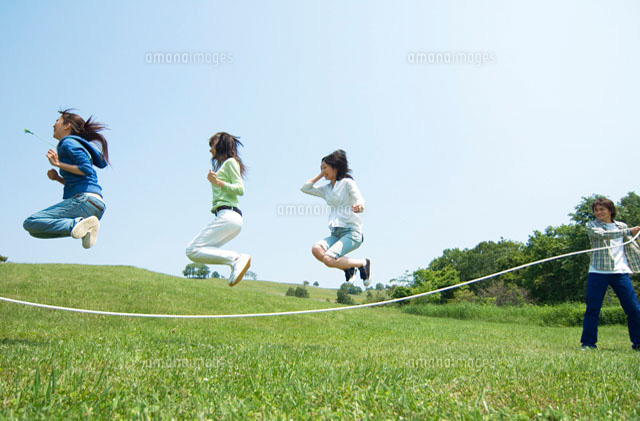 草原で縄跳びをしている3人の女性 の写真素材 イラスト素材 アマナイメージズ