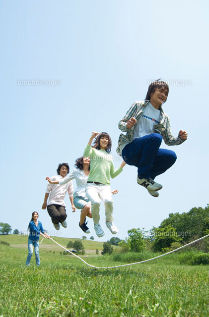 草原で縄跳びをしている若者グループ の写真素材 イラスト素材 アマナイメージズ