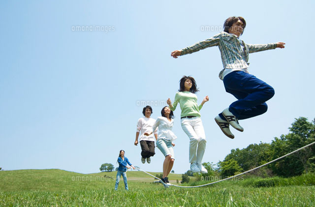 草原で縄跳びをしている若者グループ の写真素材 イラスト素材 アマナイメージズ