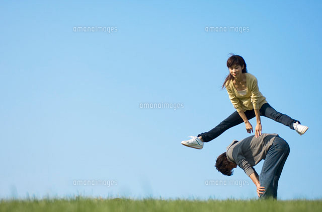 草原で馬跳びをしている若者 の写真素材 イラスト素材 アマナイメージズ