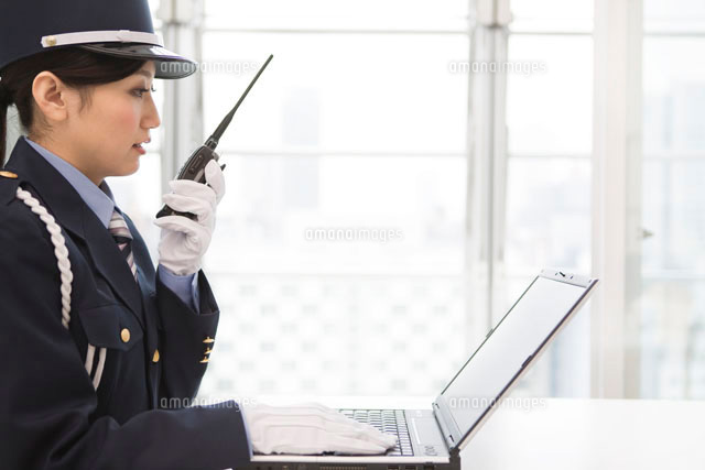 パソコンを見ながらトランシーバーで話す警備員の女性 の写真素材 イラスト素材 アマナイメージズ
