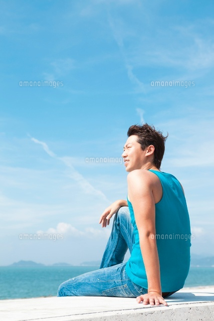 防波堤に座っている男性 の写真素材 イラスト素材 アマナイメージズ