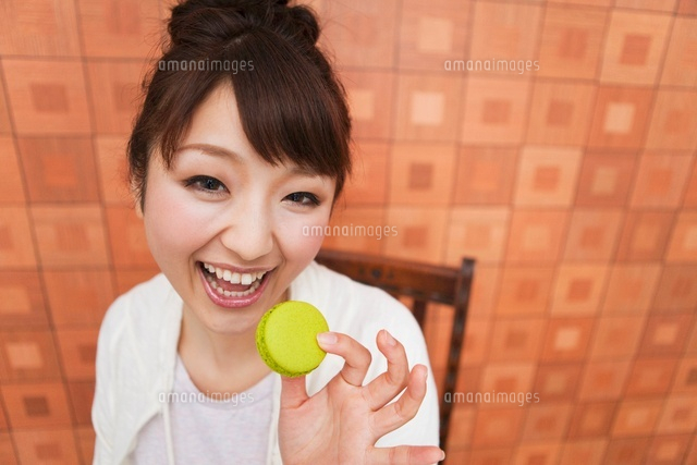 お菓子をつまむ女性 の写真素材 イラスト素材 アマナイメージズ