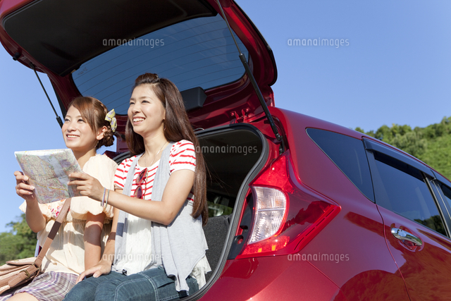 車のトランクに座る女性2人 の写真素材 イラスト素材 アマナイメージズ