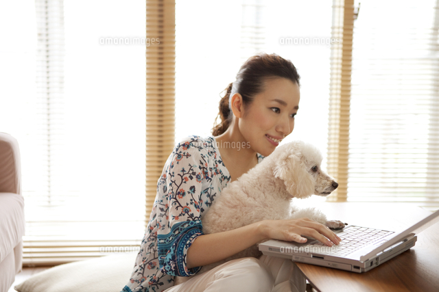 ノートパソコンを操作する女性と犬 の写真素材 イラスト素材 アマナイメージズ