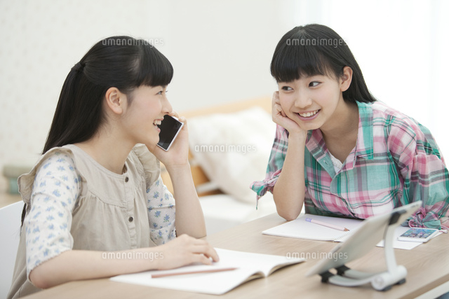 スマートフォンで通話する女の子と友達 の写真素材 イラスト素材 アマナイメージズ