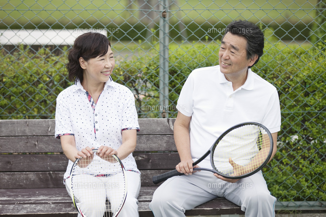 テニスコートで休憩する中高年カップル の写真素材 イラスト素材 アマナイメージズ