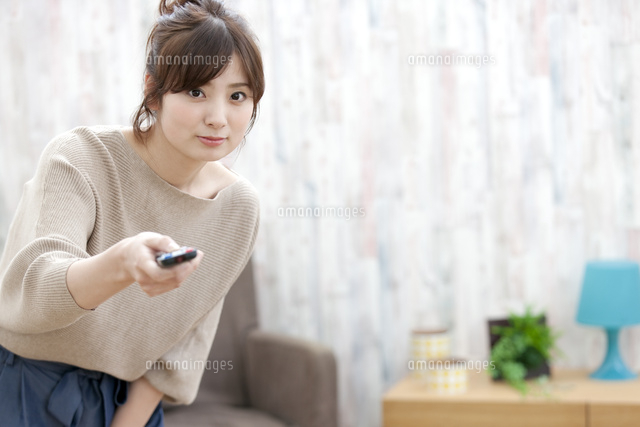 リモコンを操作する女性 の写真素材 イラスト素材 アマナイメージズ