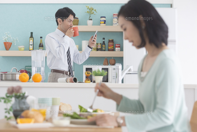 朝食を食べる女性とキッチンに立つ男性 07800060566 の写真素材 イラスト素材 アマナイメージズ