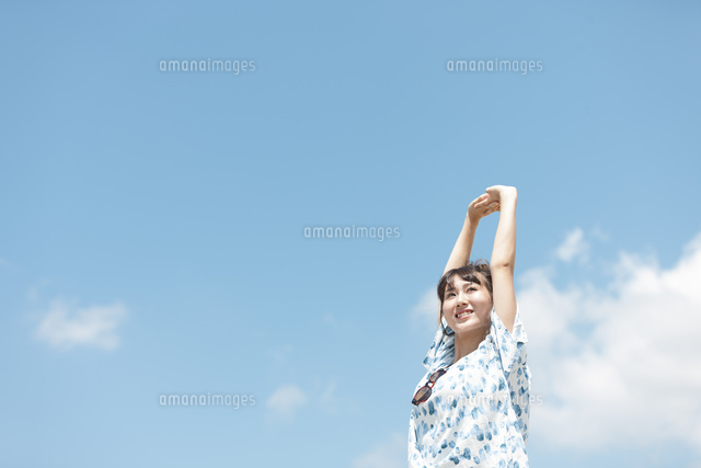 海岸で伸びをする女性 の写真素材 イラスト素材 アマナイメージズ