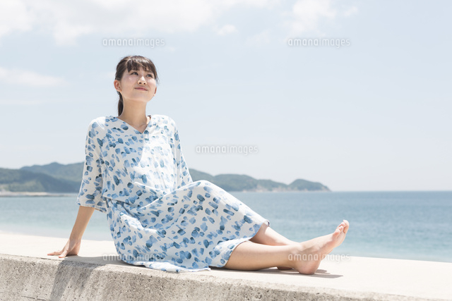 防波堤に座っている女性 の写真素材 イラスト素材 アマナイメージズ