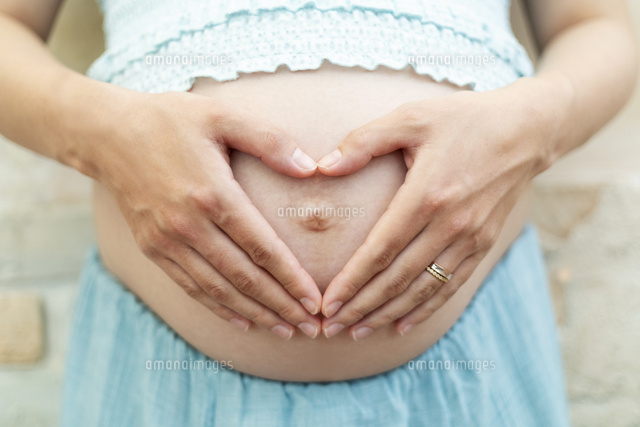 お腹に手をあてる妊婦の手元 の写真素材 イラスト素材 アマナイメージズ