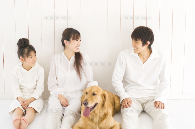 壁にもたれて座る家族と伏せる犬 の写真素材 イラスト素材 アマナイメージズ