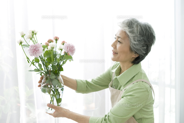 花瓶に花を生けるシニア女性 の写真素材 イラスト素材 アマナイメージズ