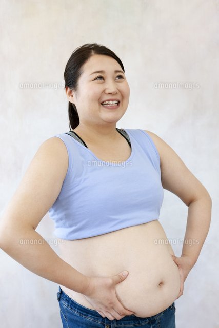 お腹に手をあてる太った女性 の写真素材 イラスト素材 アマナイメージズ