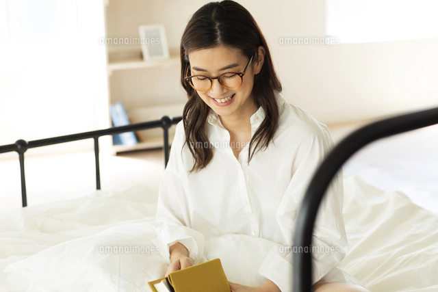 ベッドの上に寝そべる女性[10018000294]の写真・イラスト素材｜アマナ